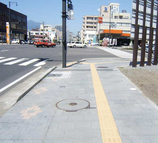 Pohled na ulici, kde jsou viditelné vodící linie vedoucí k přechodu pro chodce